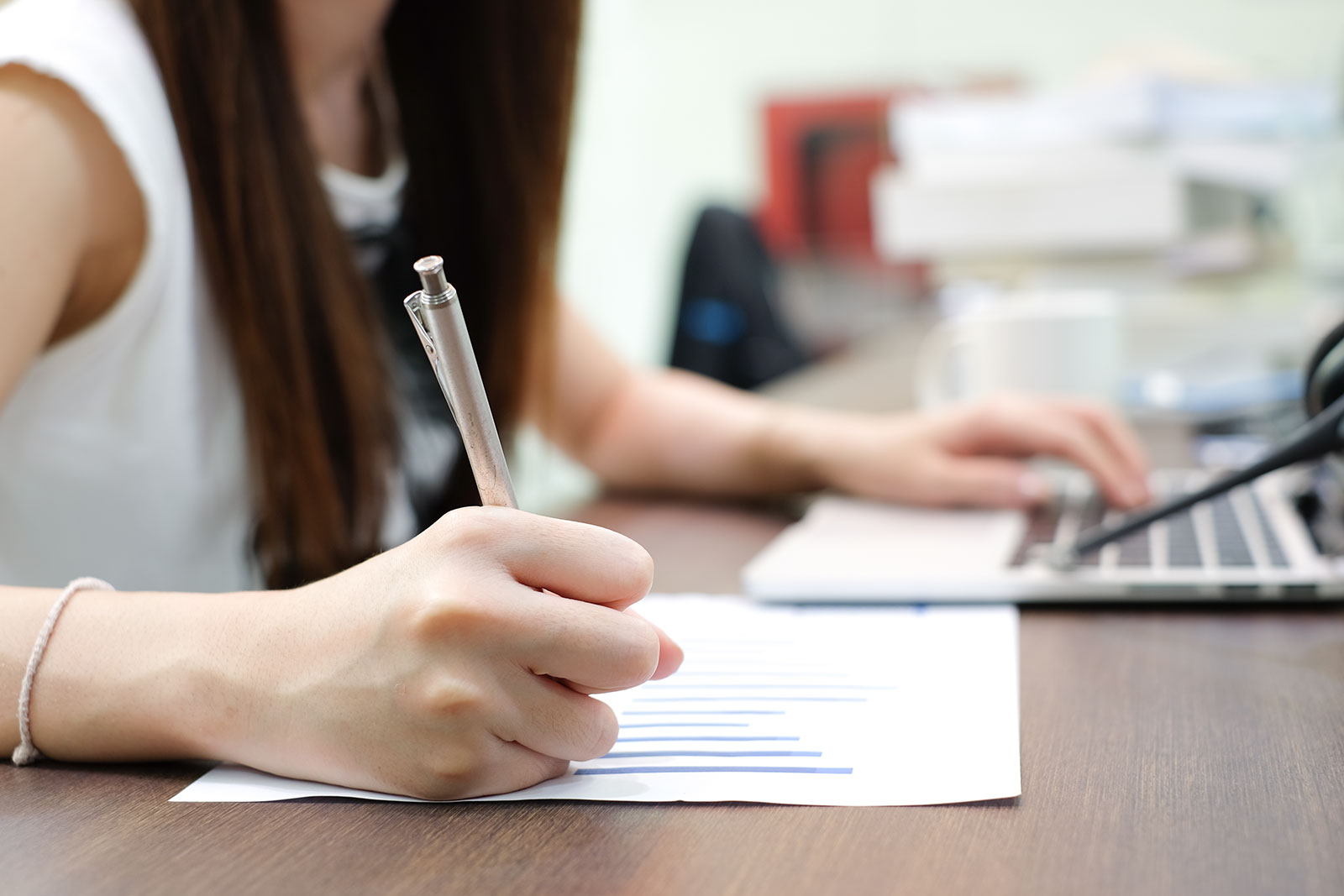 student taking notes with laptop